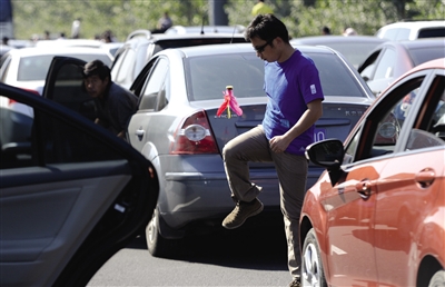 昨日,京沪高速天津段上,一名小男孩在车顶上遥望堵车长龙,甚至有车主在高速路上踢毽子、做体操消磨时间。廖攀 摄